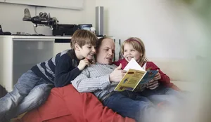 Alleinerziehende Väter Ein alleinerziehender Vater liest seinen Kindern eine Geschichte vor