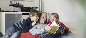 Alleinerziehende Väter Ein alleinerziehender Vater liest seinen Kindern eine Geschichte vor