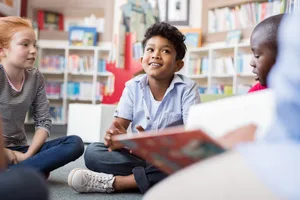 Bambini che ascoltano storie Leggere: tre bambini della scuola elementare ascoltano attentamente una storia