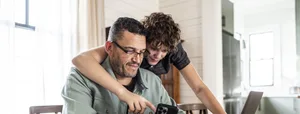 Medienabhängikeit: Ein Jugendlicher zeigt seinem Vater Inhalte auf seinem Handy Medienabhängikeit: Ein Jugendlicher zeigt seinem Vater Inhalte auf seinem Handy