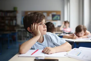 A child daydreaming, looking out of the window into a classroom Protection from the heat: primary school pupils in the classroom
