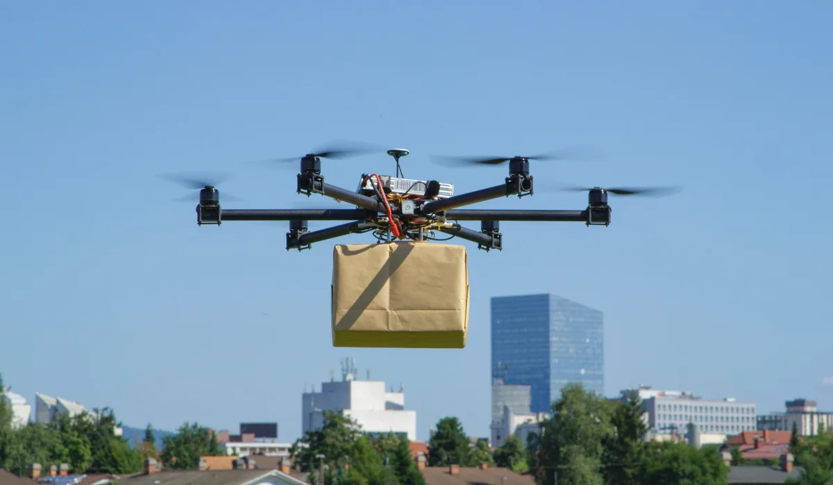 CLOSE UP: UAV drone delivery delivering big brown post package i Berufe der Zukunft: Drohnenverkehrsmanager/in