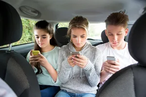 drei_Jugendliche_tippen_auf_einer_Autoru_ckbank_auf_ihr_Smartphon_ein-scaled Jugend und Medien: Hey Eltern