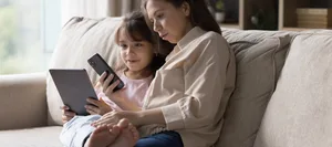 swisscom-campus-bietet-eltern-orientierung-im-digitalen-alltag Swisscom Campus: Mutter und Tochter sitzen auf dem Sofa. Die Mutter erklärt ihrer Tochter das Smartphone.