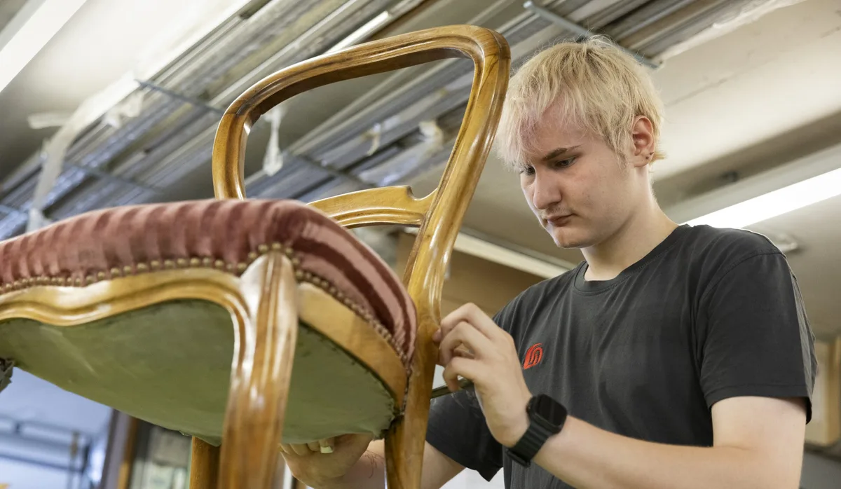 Ein Lehrling mit Handycap restauriert einen Stuhl Ein Lehrling mit Handycap restauriert einen Stuhl