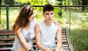 Une jolie femme assise sur un banc en été avec son fils adolescent, essayant de communiquer. Concept de la relation entre parents et adolescents Une mère est assise sur un banc avec son fils adolescent pour discuter