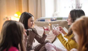 Group of small girl friends sitting on bed, eating. Übernachten: Freundinnen treffen sich zur Pijamaparty