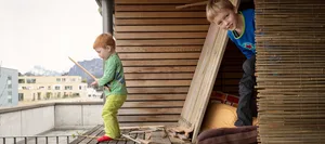 16-05-wohnen-dossier-hauptteil-schweizer-elternmagazin-hg Wie wohnen Schweizer Familien? Zwei Buben spielen auf einem Balkon einer städtischen Siedlung