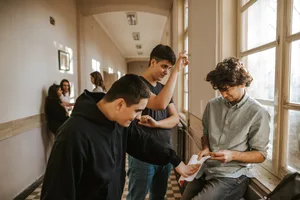 header_bullying_can_happen_to_anyone_jpg-1 Boys bullying classmate in the school corridor while girls watching