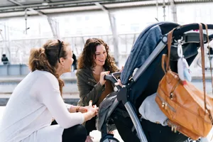 Une mère et une amie avec un bébé dans une gare de Lisbonne Une petite fille équipée d'une sonde Nsens : la mère et une amie se penchent au-dessus de la poussette