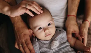 The lying baby in the hand of mother and father close-up. 4 months baby looking Seltene Krankheit, warten auf eine Diagnose: Baby wird von seinen Eltern gehalten