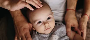 The lying baby in the hand of mother and father close-up. 4 months baby looking Seltene Krankheit, warten auf eine Diagnose: Baby wird von seinen Eltern gehalten