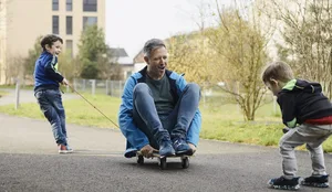 Familie Schönenberger, Mutter Janine, Vater David mit den Söhnen Joan 6 jährig (blaue Jacke) und Yannis 4 jährig Empathie: Ein Vater sitzt auf einem Skateboard und spielt mit seinen beiden Söhnen