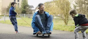 Familie Schönenberger, Mutter Janine, Vater David mit den Söhnen Joan 6 jährig (blaue Jacke) und Yannis 4 jährig Empathie: Ein Vater sitzt auf einem Skateboard und spielt mit seinen beiden Söhnen