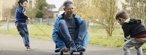 Familie Schönenberger, Mutter Janine, Vater David mit den Söhnen Joan 6 jährig (blaue Jacke) und Yannis 4 jährig Empathie: Ein Vater sitzt auf einem Skateboard und spielt mit seinen beiden Söhnen