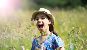Ein Mädchen steht in einer wilden Blumenwiese im Thüringer Wald Zecken, Zeckenstich: fröhliches Mädchen in hoher Blumenwiese