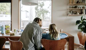 Rear view mother guiding son doing homework while sitting on chair near table at home Trennung: Eine Mutter mit ihrer Tochter am Esstisch