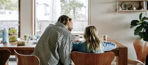 Rear view mother guiding son doing homework while sitting on chair near table at home Trennung: Eine Mutter mit ihrer Tochter am Esstisch