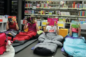 Kinder-bei-Lesenacht-im-Schlafsack-hinter-Bu_chern-scaled Wo sich kleine und grosse Bücherwürmer treffen