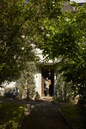 26-07-infanzia-felicità-rivista-svizzera-per-genitori-ed Felicità e infanzia: una madre tiene in braccio suo figlio davanti all’ingresso di casa sua