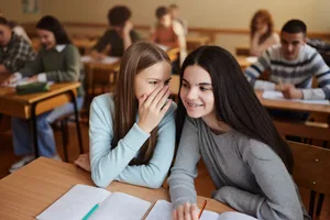 Deux filles chuchotent dans la salle de classe. Un malentendu surgit. Deux filles chuchotent dans la salle de classe. Un malentendu surgit.