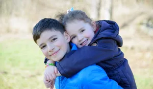 Huckepack Geschwister: ein älterer Bruder nimmt seine Schwester Huckepack