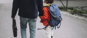 A low-angle shot of a father and son holding hands and walking along a footpath Separation: Father and son walk hand in hand