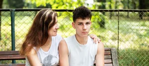 Una bella donna seduta su una panchina d’estate con il figlio adolescente, mentre cercano di comunicare. Il concetto di relazione tra genitori e adolescenti La madre è seduta su una panchina con il figlio adolescente per fare due chiacchiere