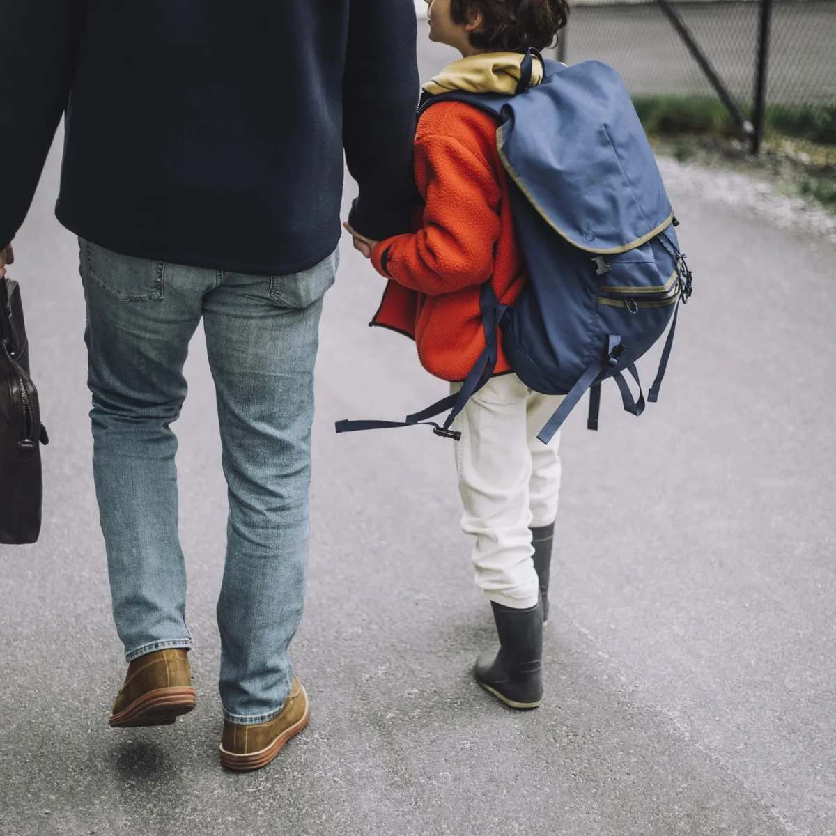 Low section of father and son holding hands and walking on footpath Trennung: Vater und Sohn spazieren Hand in Hand