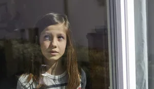Einzelkind im Lockdown Verträumte Kinder: Ein Mädchen blickt durch ein Glasfenster.