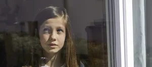 Einzelkind im Lockdown Verträumte Kinder: Ein Mädchen blickt durch ein Glasfenster.