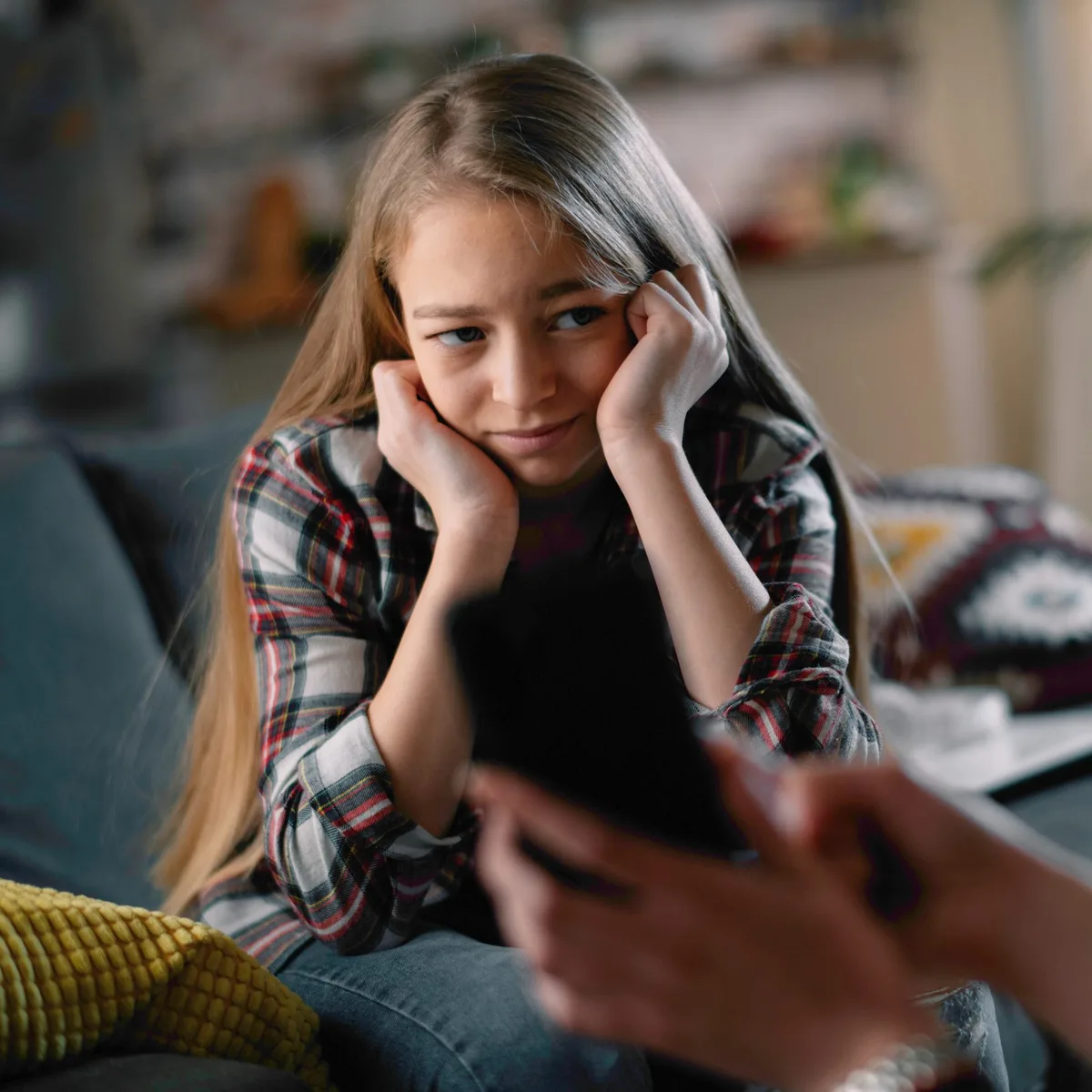 Eine Jugendliche sitzt frustriert auf dem Sofa, wird von der Mutter ermahnt. Eine Jugendliche sitzt frustriert auf dem Sofa, wird von der Mutter ermahnt.