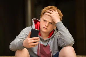 Société_Psychologie_Thérapie_en_ligne_Screenkids_garçon_triste_Smartphone Thérapie dans un salon de discussion ?