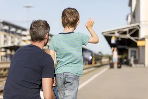 Fils avec son père faisant signe à sa mère sur le quai Parents célibataires : un garçon est avec son père et fait signe à sa mère