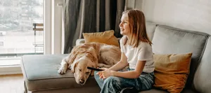 medien-srf-kids-schweizer-elternmagazin-hg Medien. Mädchen schaut TV und sitzt mit dem Hund auf dem Sofa.