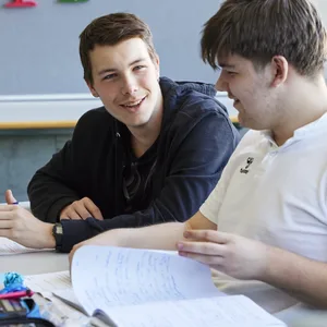 26-07-glueck-als-schulfach-schweizer-elternmagazin-hg Glück als Schulfach: Zwei Schüler reden im Schulzimmer miteinander