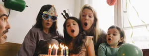 Kindergeburtstag: Familie bläst Kerzen auf der Torte aus. Kindergeburtstag: Familie bläst Kerzen auf der Torte aus.