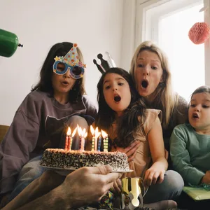 Kindergeburtstag: Familie bläst Kerzen auf der Torte aus. Kindergeburtstag: Familie bläst Kerzen auf der Torte aus.