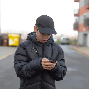 Male pedestrian concentrating on smartphone amidst cityscape under gray sky Männlicher Teenager am Smartphone