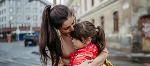 Mother hugging daughter on a city street. Young girl with anxiety doesn’t want to go to school. Fear of bullying. Empathie: Eine Mutter tröstet ihre Tochter