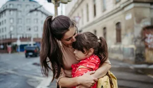 Mother hugging daughter on a city street. Young girl with anxiety doesn’t want to go to school. Fear of bullying. Empathie: Eine Mutter tröstet ihre Tochter