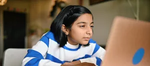 Girl using a laptop and looking at it with strained eyes Kurzsichtigkeit: Ein Mädchen sitzt vor dem Laptop