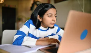 Girl using a laptop and looking at it with strained eyes Kurzsichtigkeit: Ein Mädchen sitzt vor dem Laptop