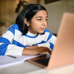Girl using a laptop and looking at it with strained eyes Kurzsichtigkeit: Ein Mädchen sitzt vor dem Laptop