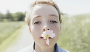 Portrait of boy with blossom in his mouth Bub mit Blume im Mund