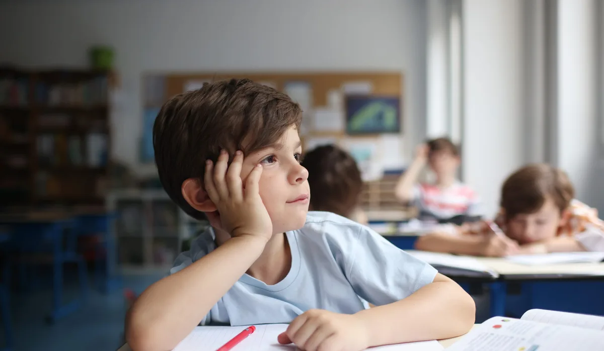A child daydreaming, looking out the window into a classroom Schutz vor Hitze: Primarschüler im Klassenzimmer