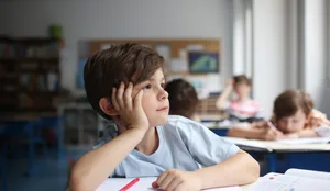 A child daydreaming, looking out the window into a classroom Schutz vor Hitze: Primarschüler im Klassenzimmer