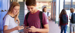 swisscom-handys-handyverbot-schule-schweizer-elternmagazin-hg Zwei Teenager mit Handys in der Schule