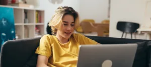 un adolescent allongé sur le canapé chez lui, en train d’utiliser un ordinateur portable L'IA peut-elle aider à choisir un métier ? Un garçon est assis devant son ordinateur portable.