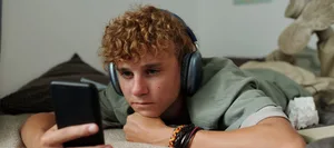 Hatespeech: Jugendlicher im Bett am Handy Hatespeech: Jugendlicher im Bett am Handy